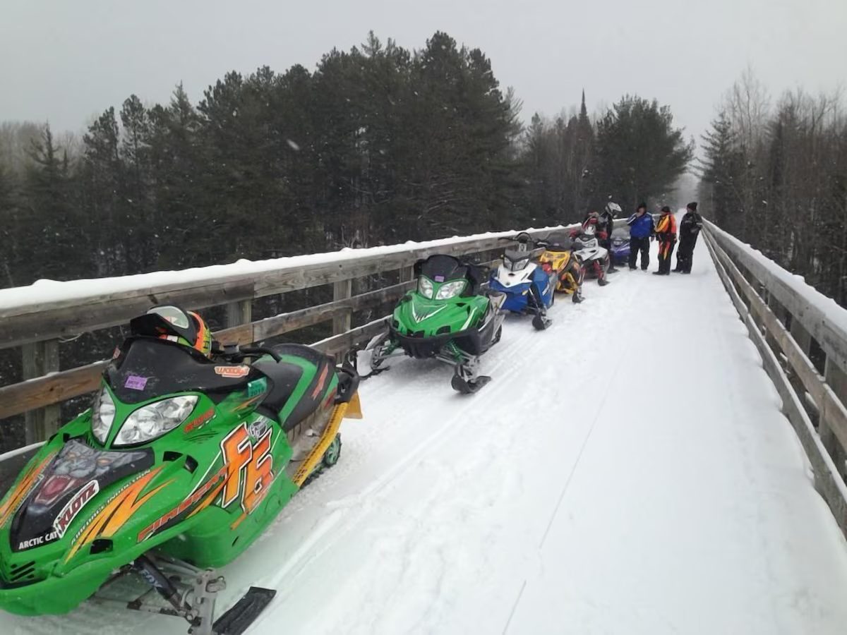 Snowmobiles parked on the snowy trail bridge on Trail 116 near Chicaugon Lake