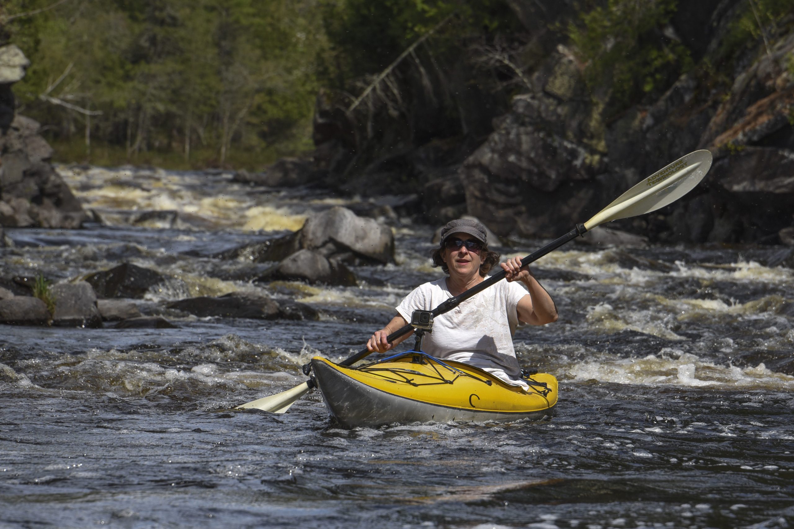 Kayaking down the rapids, navigating rocks on a river in Iron County, Michigan, on a cloudy day.