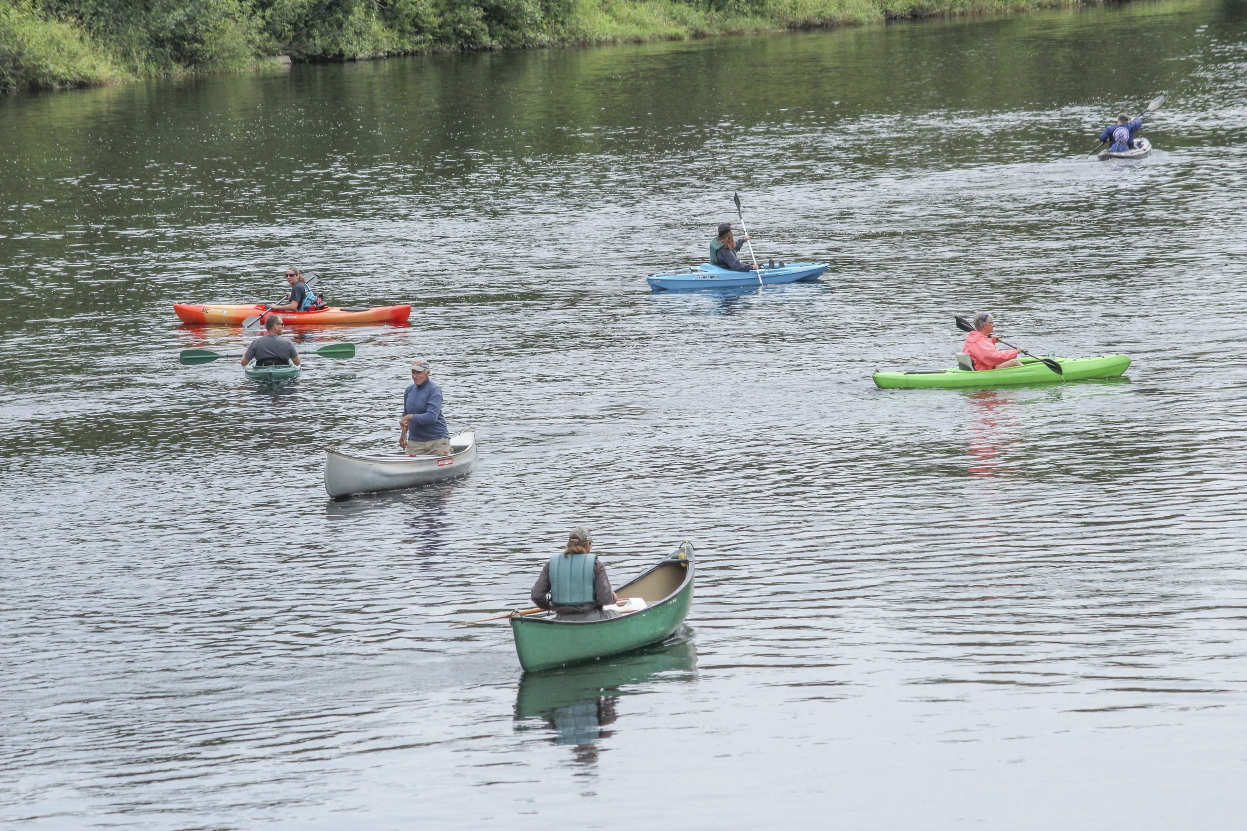 Kayakers and canoeists paddling across a calm Iron County lake on a summer day