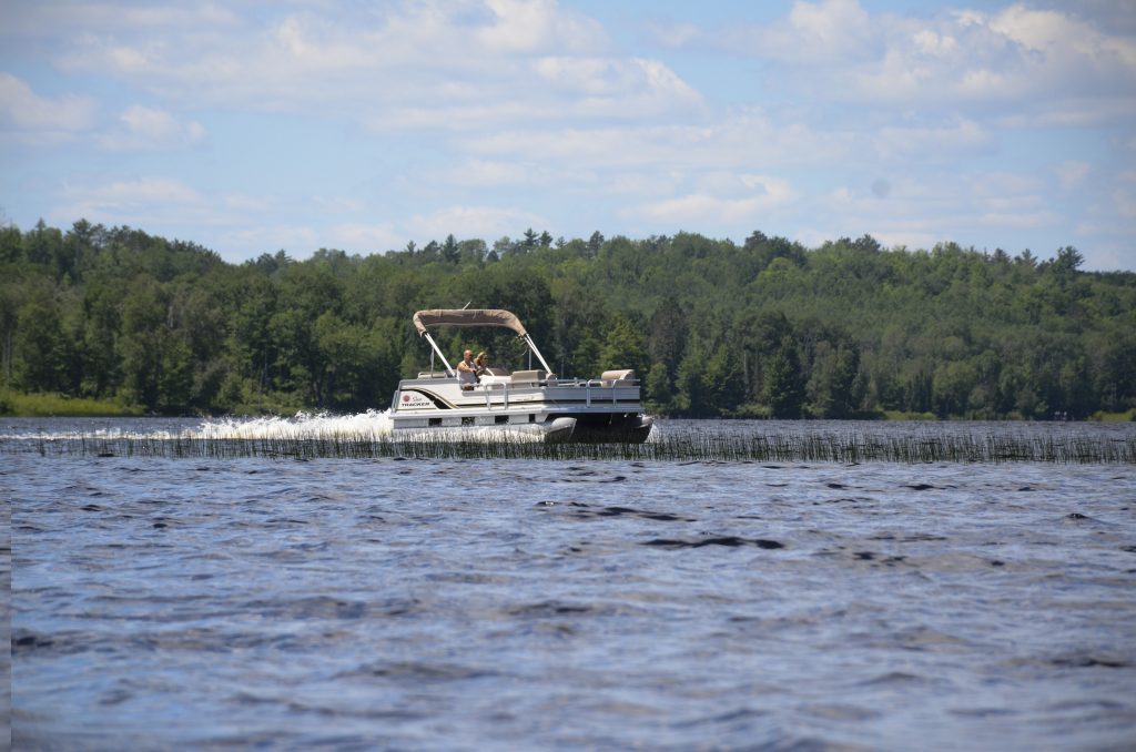 A couple enjoying a pontoon ride on a lake in Iron County Michigan on a nice day.