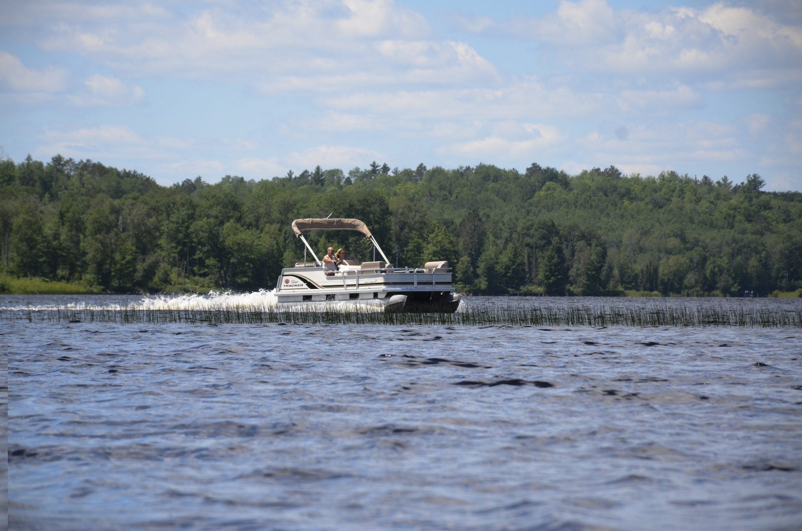 A couple enjoying a pontoon ride on a lake in Iron County Michigan on a nice day.