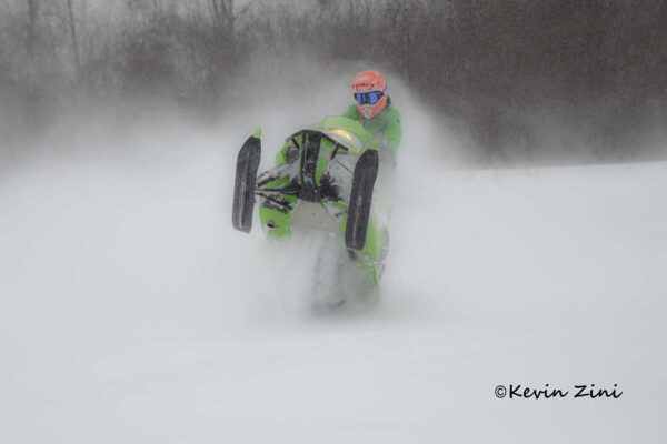 lime greeb full throttle snowmobile wheelie on fresh powder,