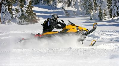 action shot of a yellow snowmobile popping a wheelie