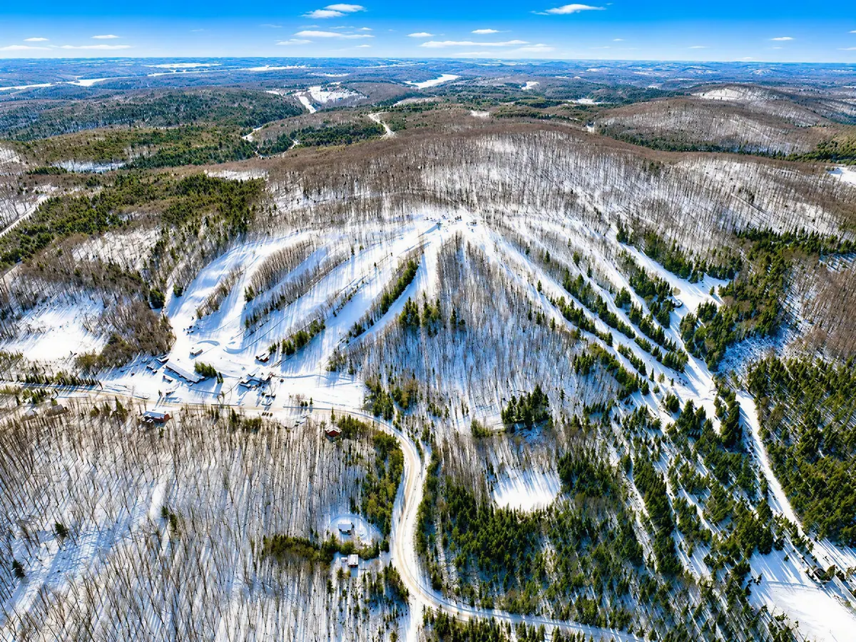 Aerial view of Ski Brule's snow-covered runs cutting through the forest near Iron River