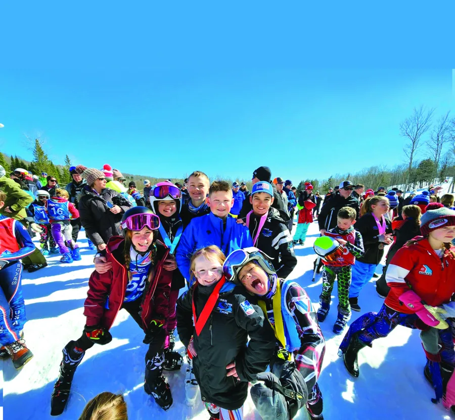 A crowd of kids in ski helmets and goggles cheering at the bottom of the hill at Ski Brule