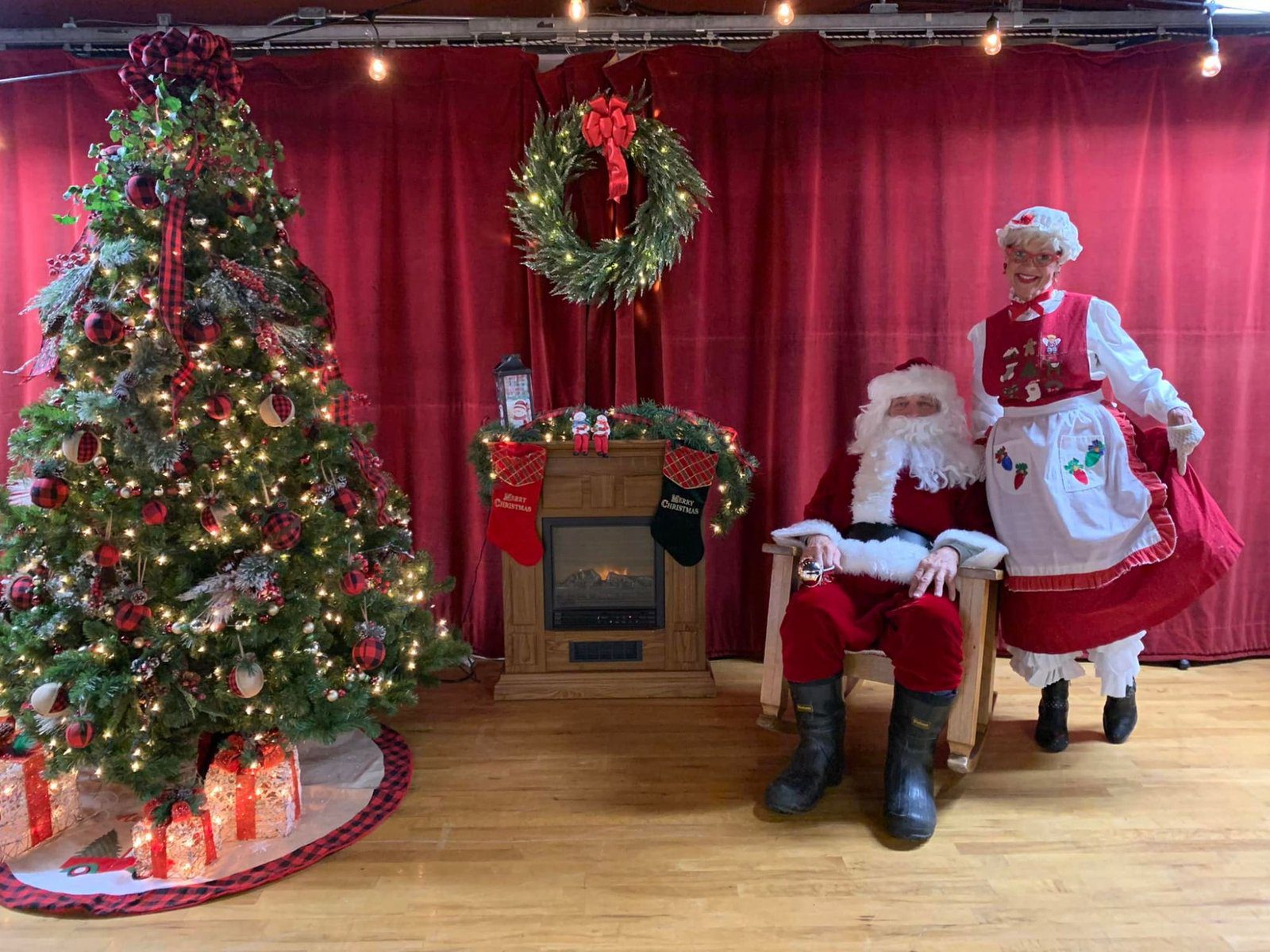 Santa and Mrs. Claus seated by a decorated tree and a fireplace at the Christmas Tree Galleria in Caspian