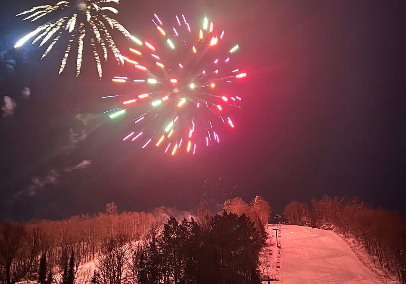 Fireworks bursting over the lit ski hill at Ski Brule on New Year's Eve