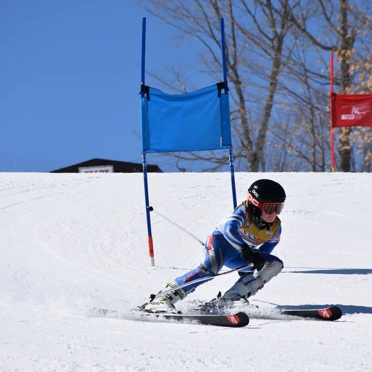 young Skier carving down a snowy slope in Iron County, Michigan, with trees in the background.